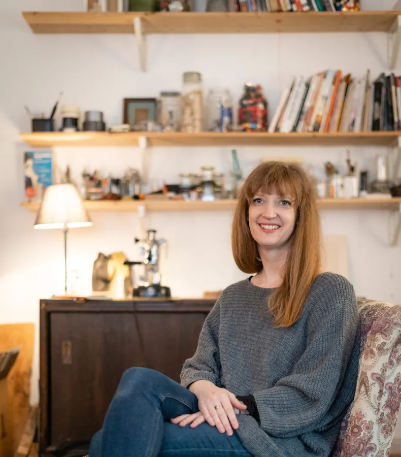 Brooke Meenan smiling, sitting in an armchair in her studio