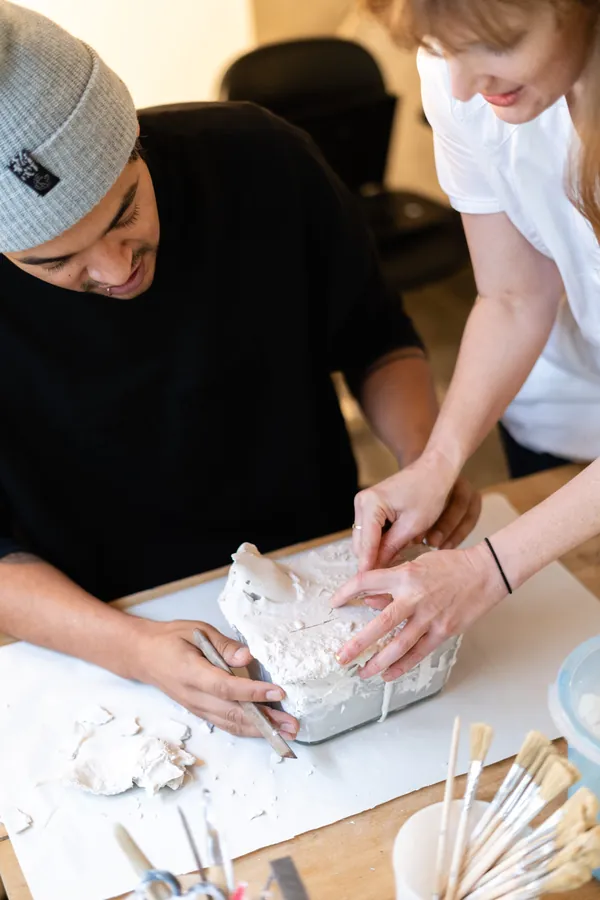 Brooke helping a workshop participant free a plaster cast from its mould