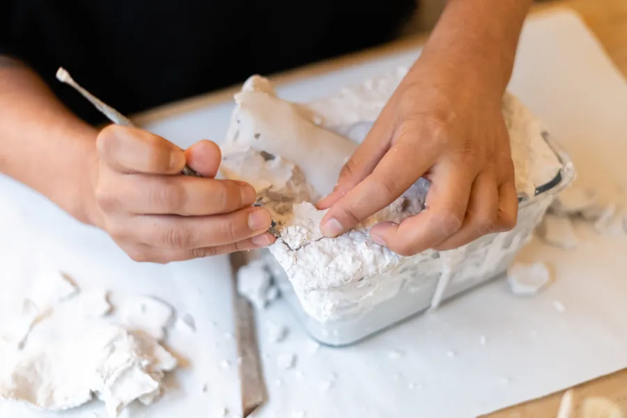 Hands carefully freeing a plaster cast from its mould during a workshop